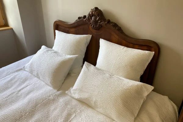 Lit double confortable du gîte Maison Stendhal aux Échelles en Savoie avec linge de lit blanc